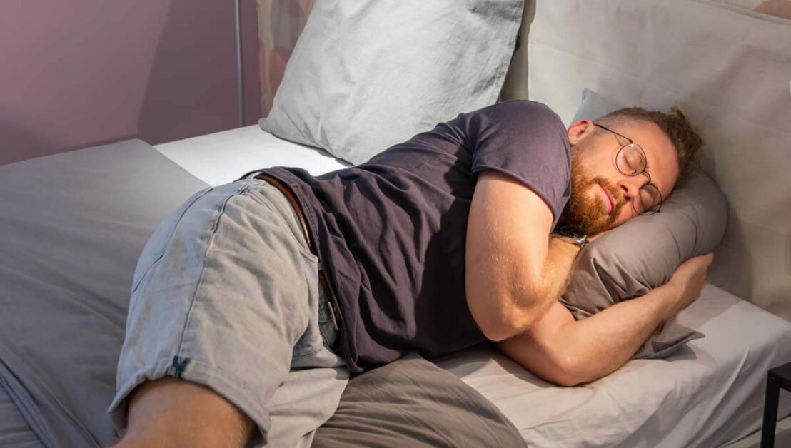 Young guy man beard fell asleep in glasses on a bed
