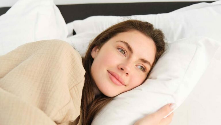 young woman hugging her pillow and smiling while sleeping